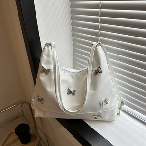 Sac fourre-tout blanc en cuir souple avec papillons argentés sur un rebord de fenêtre