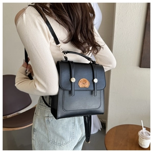 Detail of a black mini backpack with golden buckles and cute brown dog embroidery