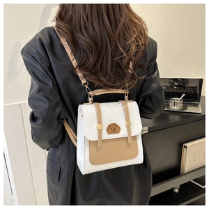 Detailed back view of a white and brown patchwork backpack with poodle embroidery