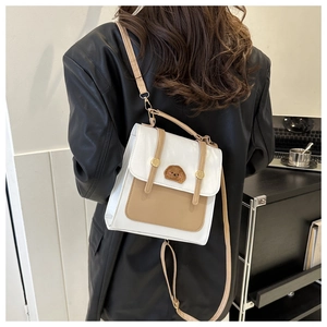 Detail of white and khaki crossbody bag featuring cartoon dog patch and gold magnetic buckles