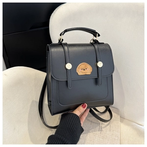 Detail of black square PU leather backpack with plush dog patch and gold metal buckles