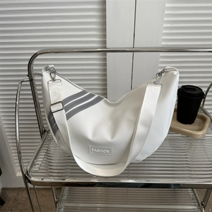 White nylon crescent shoulder bag with fashion label and grey stripes on a modern background