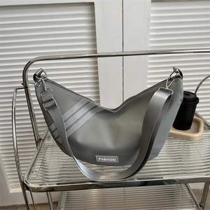 Grey nylon half-moon crossbody bag with fashion label and three side stripes on a glass cart