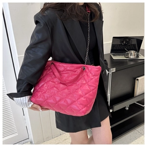 Macro view of rose red quilted faux leather tote with elegant gold chain strap detail