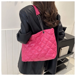 Quilted hot pink PU leather tote bag with silver chain strap shown on black leather coat