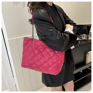 Detail view of large magenta quilted tote bag with chain strap worn on the shoulder