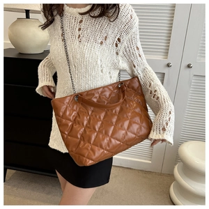 Close-up of brown quilted tote bag with large diamond stitching and metal chain strap