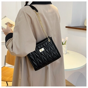 Chic black quilted crossbody bag with golden chain and clasp shown on a model