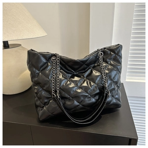 Detail of black quilted large tote bag with silver chain strap and leather stitching