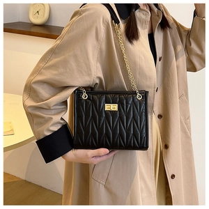 Detail of quilted leather shoulder bag with golden chain strap and swivel lock closure