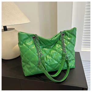Detail of green quilted tote bag with metallic chain straps and glossy PU texture