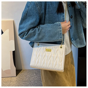 Detail shot of white quilted crossbody bag with gold chain strap and turn-lock closure