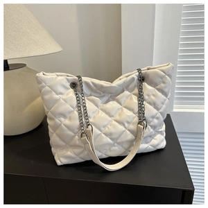Detailed view of white quilted faux leather tote bag with elegant metal chain shoulder strap