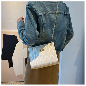 Close-up of a white V-quilted faux leather crossbody bag with golden chain and square lock