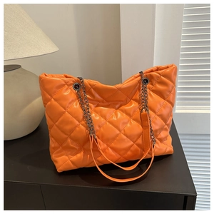 Detail of orange quilted tote bag with metallic chain and faux leather shoulder strap