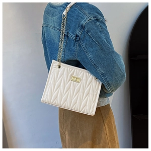 Detail of white quilted leather bag with wave texture and gold chain strap on model
