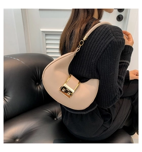 Detail of apricot crescent bag featuring round curves and a signature gold metal clasp