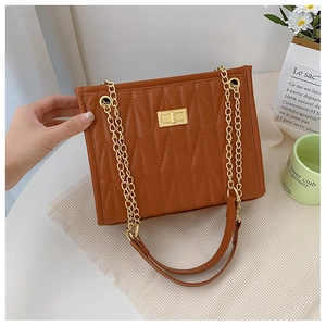 Detail of brown chevron quilted bag featuring golden twist lock and metal chain strap