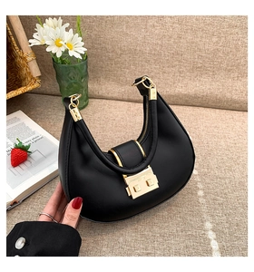 Close-up of black hobo bag with gold magnetic buckle on beige textured background