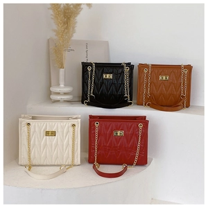 Close-up of four colors of quilted shoulder bags with gold chain straps and metal twist locks