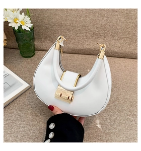 Close-up of a white crescent shoulder bag with smooth faux leather and gold buckle