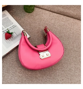 Detail of pink crescent handbag featuring gold snap closure and integrated round handle