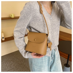 Brown lychee leather bucket bag with woven strap and elephant charm detail