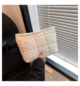 Nahaufnahme der cremeweißen Stepp-Clutch mit goldenem Reißverschluss und Rautenmuster