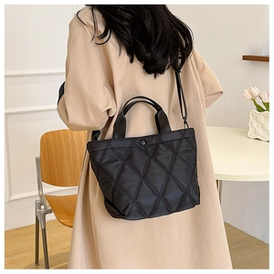 Détail du sac cabas matelassé noir en nylon avec poignées larges et bandoulière amovible