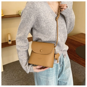Detail of tan PU leather crossbody bucket bag with elephant charm and braided strap