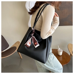 Detail of black tote bag with woven shoulder strap and decorative silk scarf in cafe