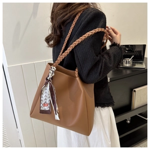 Detail of a large brown PU leather tote bag with braided straps and decorative floral scarf