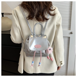 Detail of silver mini backpack with pink drawstring beads and plush monster charm
