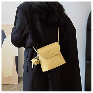 Detail of yellow pebbled leather crossbody bag with cute elephant charm on black blazer