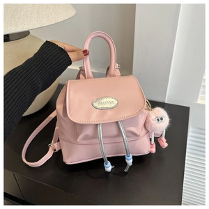 Detail of pink mini backpack with silver logo, beaded drawstring and furry monster charm