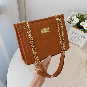 Quilted caramel brown chain shoulder bag with gold twist lock in a minimalist setting