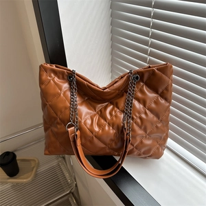 Brown quilted leather tote bag with chain strap shown on a bright indoor windowsill