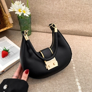 Minimalist black crescent shoulder bag with golden hardware on a soft beige background
