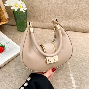 Elegant beige half-moon handbag with gold hardware displayed on a stylish textured background