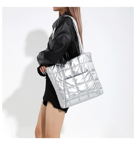 Silver quilted tote bag in metallic finish worn by model as a stylish shoulder bag
