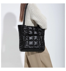 Detailed view of black quilted tote bag showing square stitching and glossy texture