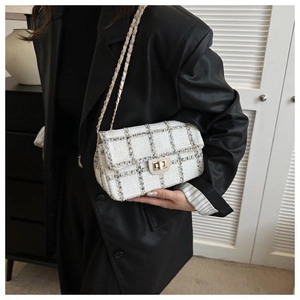 Détail du sac bandoulière en tweed blanc et bleu avec chaîne dorée et fermoir métal