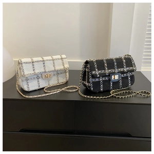 Détail de sacs à rabat en tweed noir et crème avec chaînes dorées et fermoirs métalliques