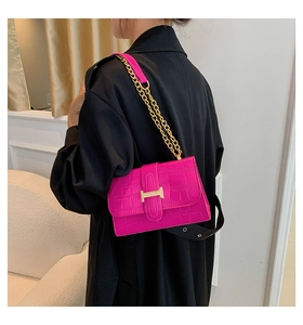 Detail view of fuchsia crocodile pattern crossbody bag with a golden H buckle and chain