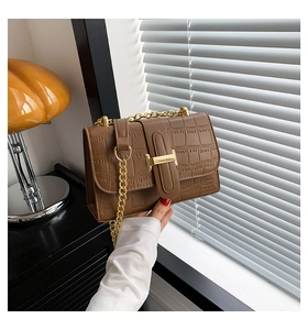 Close-up of brown crocodile texture flap bag with gold H-clasp and elegant chain strap