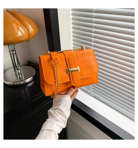 Close-up of orange faux crocodile skin texture and iconic gold H-buckle detail