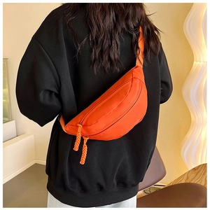 Detail der leuchtend orangefarbenen Nylon-Brusttasche mit verstellbarem Gurt am Model