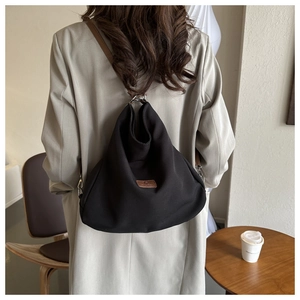 Detailed view of the large black canvas tote with leather patch and brown strap