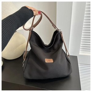 Detail of black nylon tote bag with brown leather handles and silver metal hardware