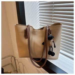 Detail of beige tote bag with brown straps and cute brown sheep plush keychain charm